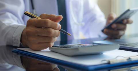 Eigenrisicodrager Ziektewet; man met een telefoon en een pen in zijn hand maakt berekeningen op zijn rekenmachine
